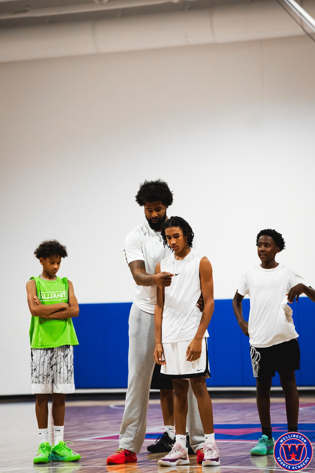 Coach guiding a young player while two other players watch