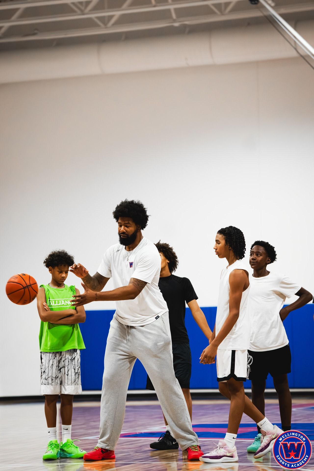 Coach demonstrating a ball-handling move to four attentive young players