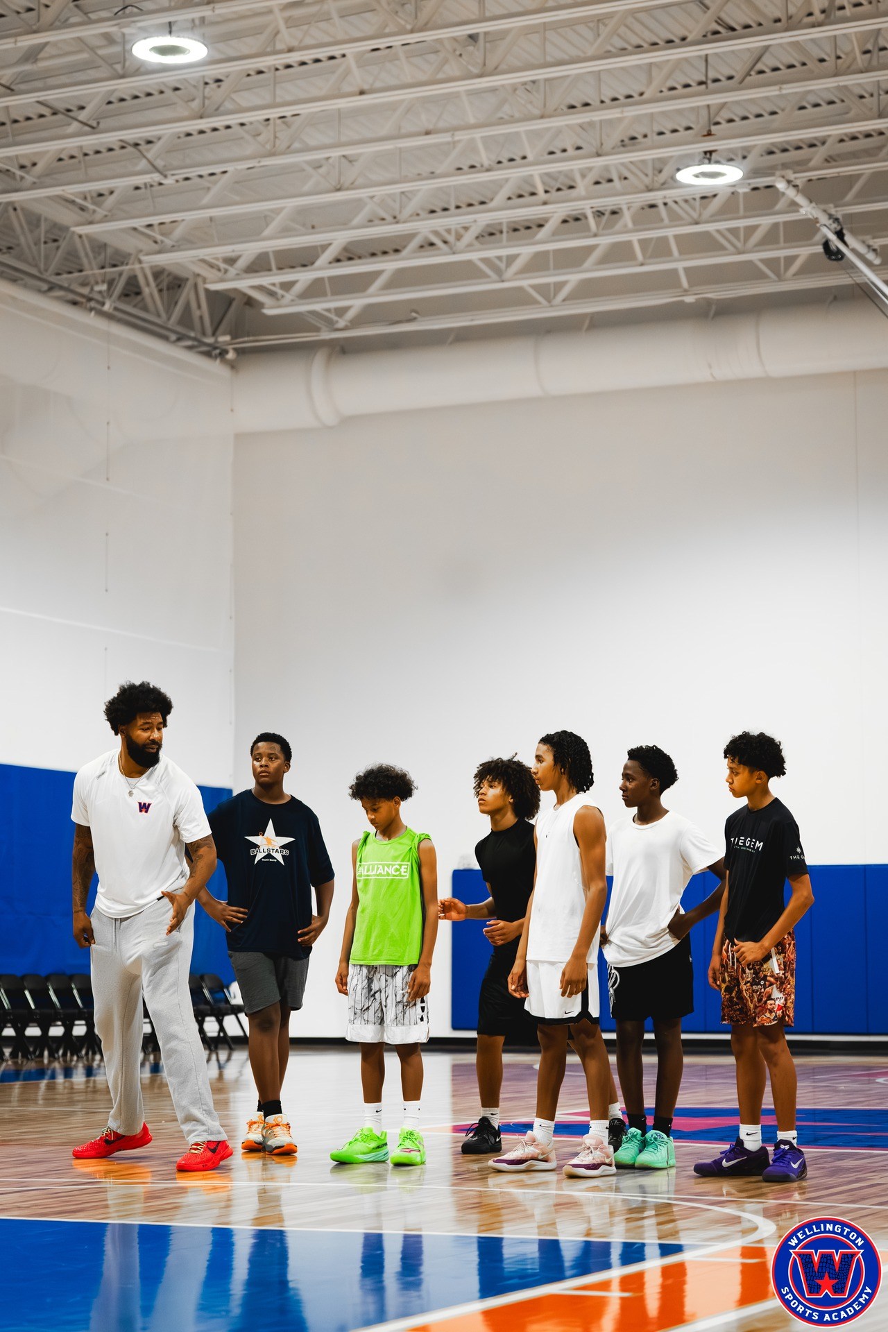 Coach speaking to a line of six young players spread across the court