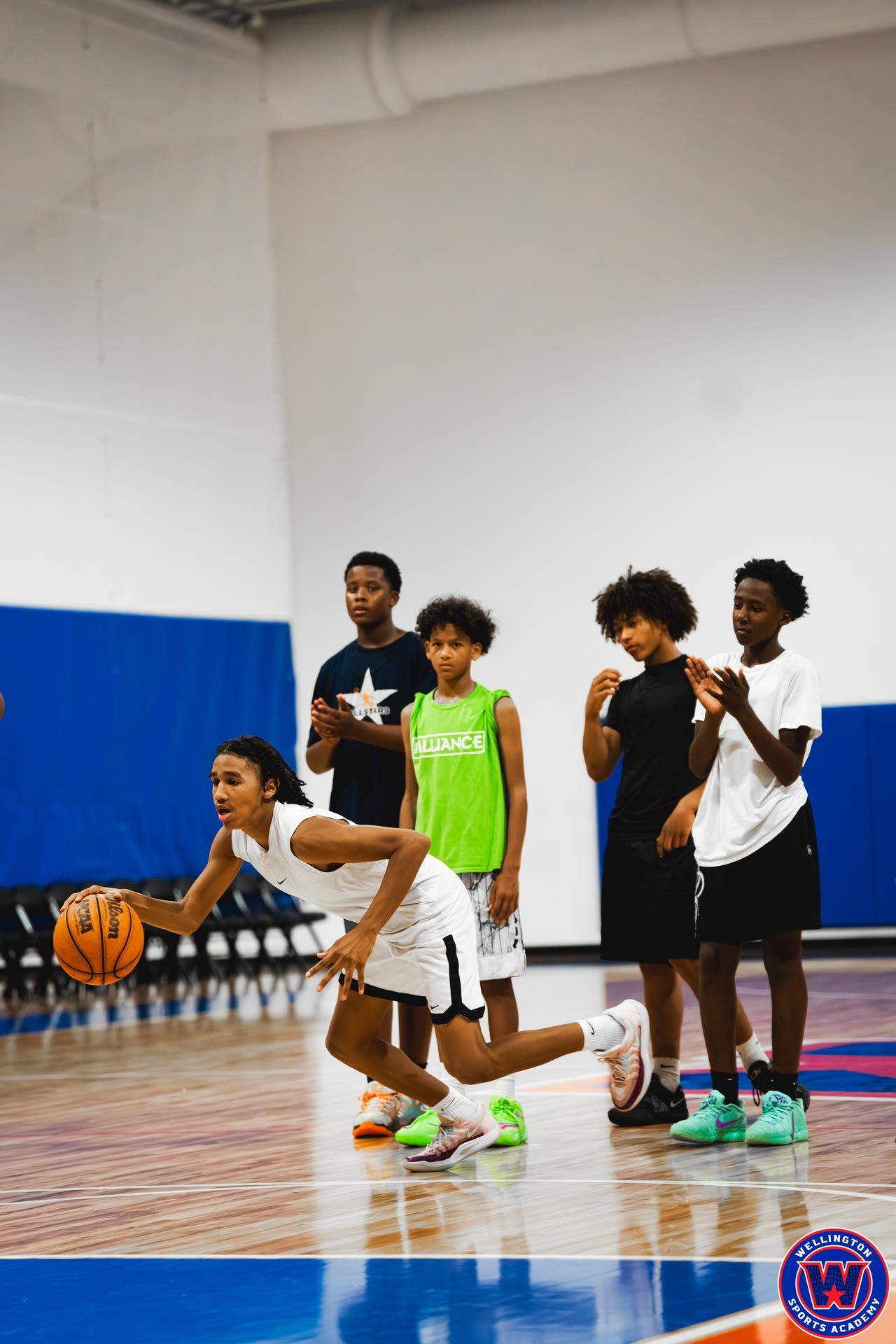 Young player executing a low dribble drill while teammates look on and react