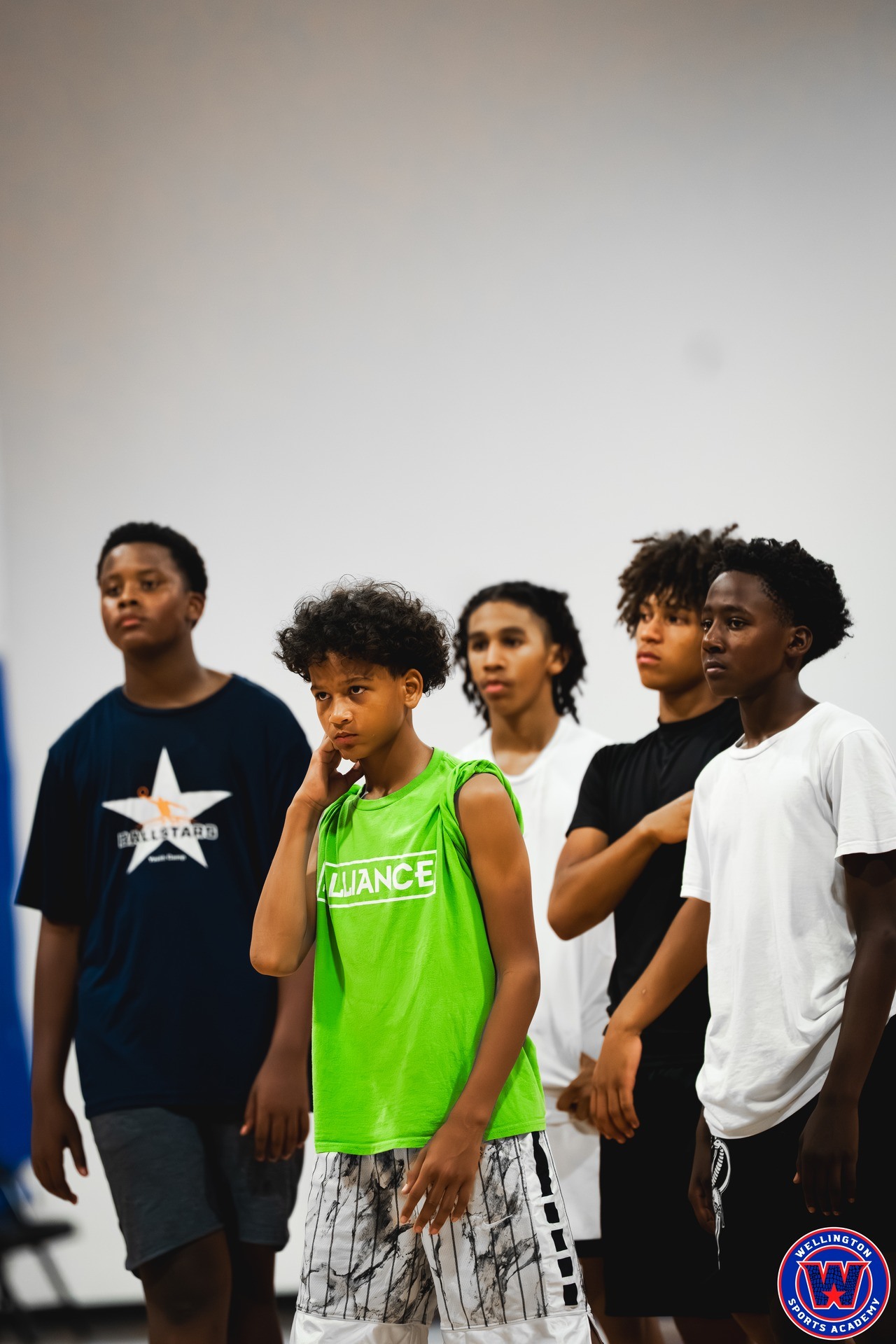 Five young players standing together listening attentively during a coaching session