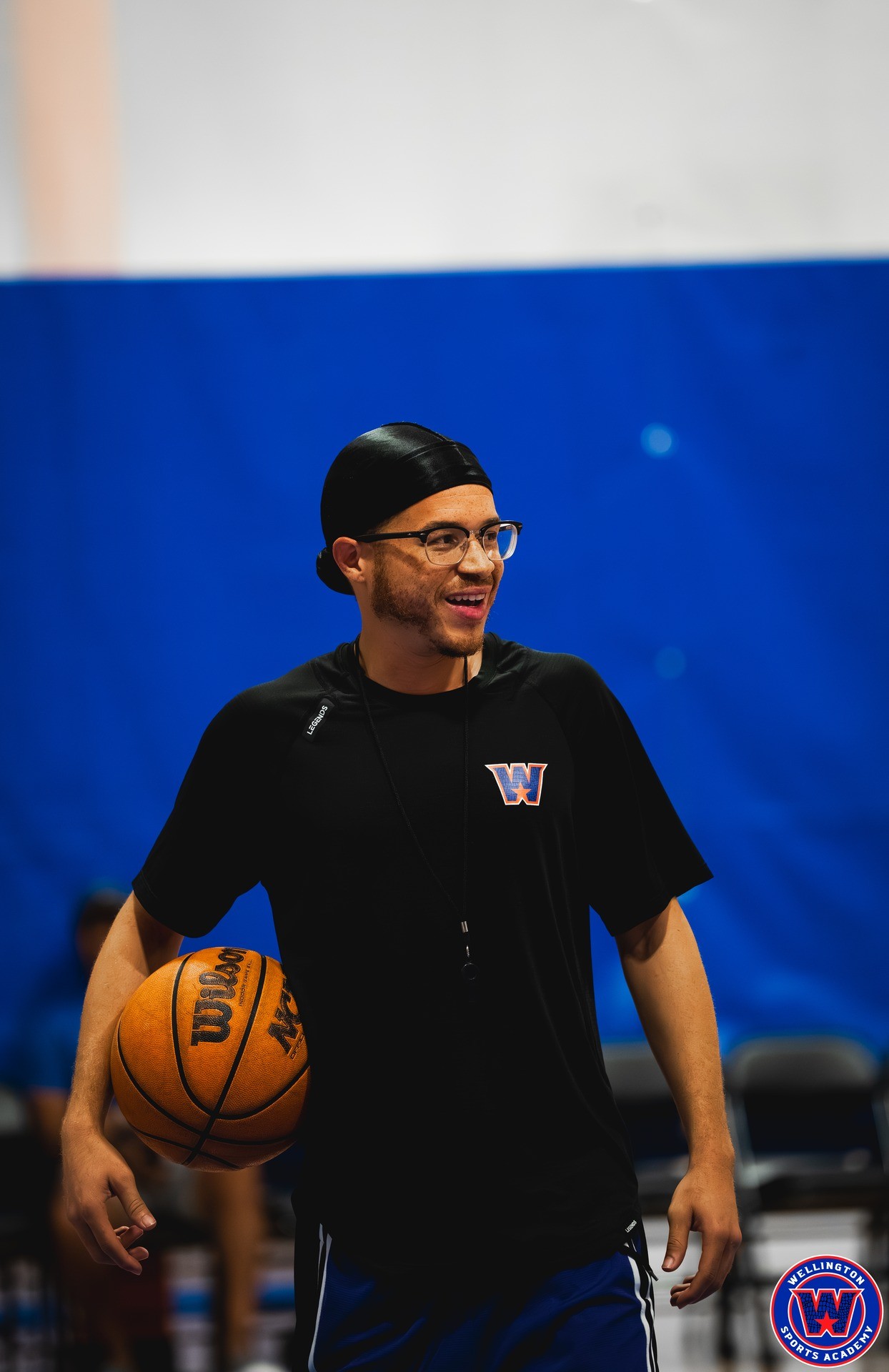 WSA coach in black shirt and glasses, smiling during practice