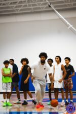 Coach dribbling at the front while six young players observe from behind