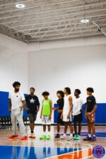 Coach speaking to a line of six young players spread across the court