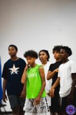 Five young players standing together listening attentively during a coaching session