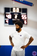 Close portrait of WSA coach in white shirt, scoreboard lit up 48–55 behind him