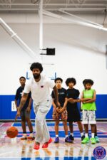Coach dribbling to demonstrate a move while players watch from behind