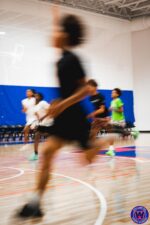 Motion-blurred players running court sprints during a conditioning drill